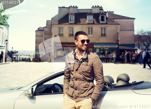 Image of happy man driving cabriolet car over city