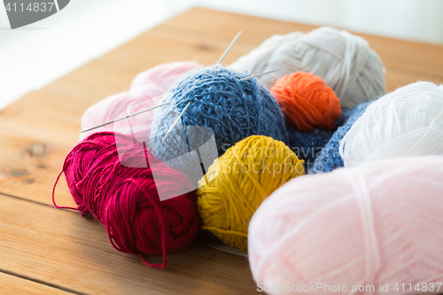 Image of knitting needles and balls of yarn on wood