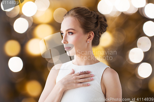 Image of woman in white with diamond ring and earring