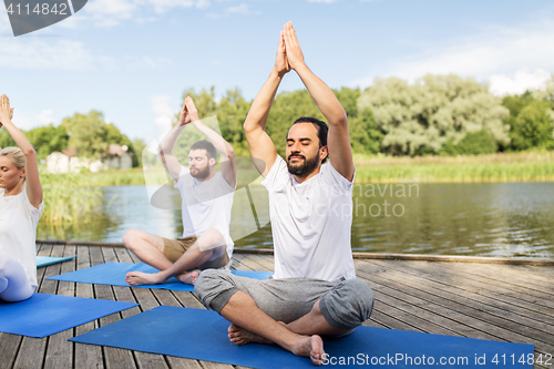 Image of people meditating in yoga lotus pose outdoors