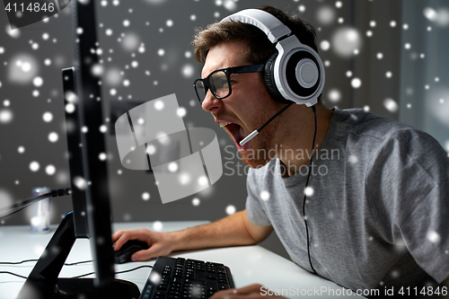 Image of man in headset playing computer video game at home