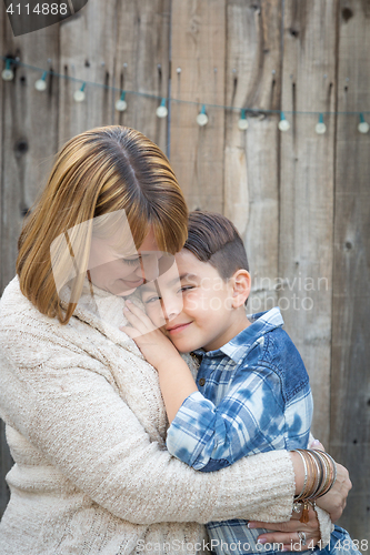 Image of Mother and Mixed Race Son Hug Near Fence