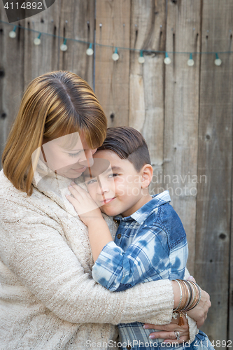 Image of Mother and Mixed Race Son Hug Near Fence