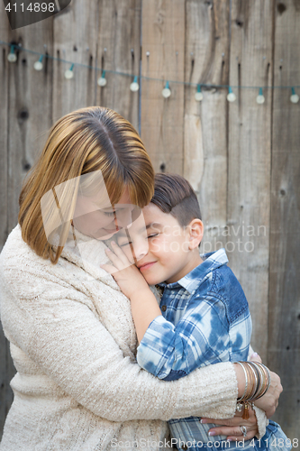 Image of Mother and Mixed Race Son Hug Near Fence