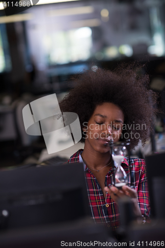 Image of young woman at office looking at sand  clock