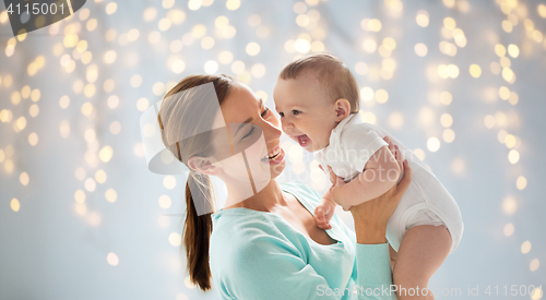 Image of happy young mother with little baby over lights