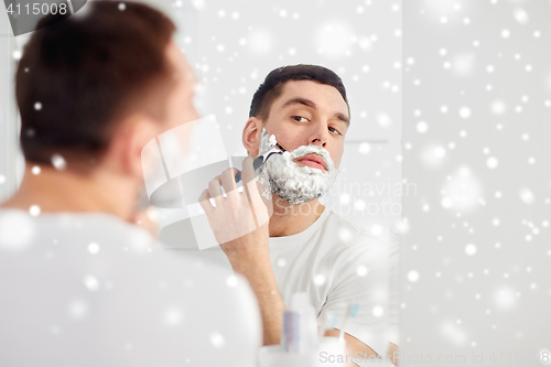 Image of man shaving beard with razor blade at bathroom