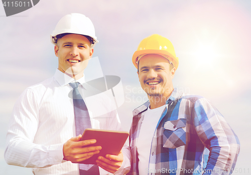 Image of smiling builders in hardhats with tablet pc