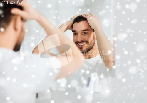 Image of happy young man looking to mirror at home bathroom