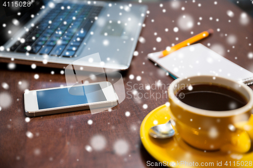 Image of close up of smartphone, coffee cup and laptop