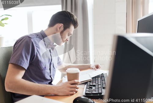 Image of creative male worker drinking coffee and reading