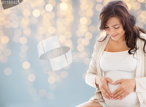 Image of happy pregnant woman making heart gesture in bed