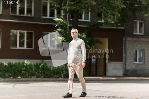 Image of senior man walking along summer city street