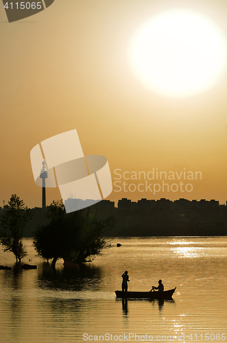 Image of silhouette of fishermen with and orange sun 