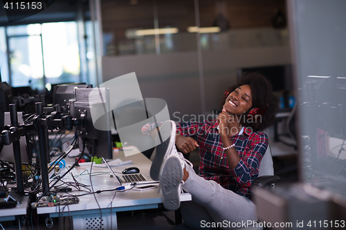 Image of woman at her workplace in startup business office listening musi