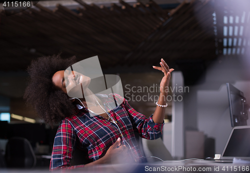 Image of woman at her workplace in startup business office listening musi