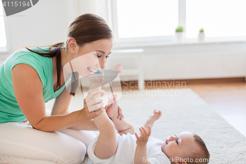 Image of happy mother playing with little baby at home