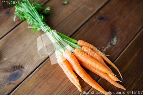 Image of close up of carrot bunch on wooden table