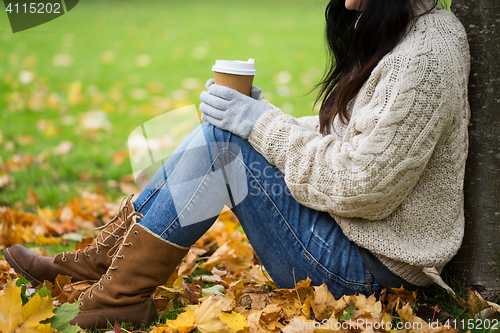 Image of close up of woman drinking coffee in autumn park