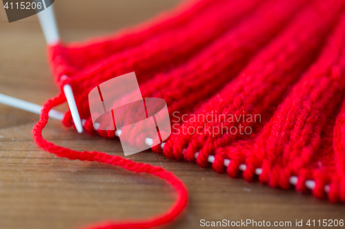 Image of hand-knitted item with knitting needles on wood