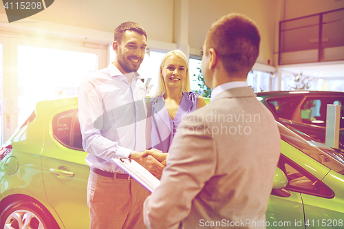 Image of happy couple with car dealer in auto show or salon