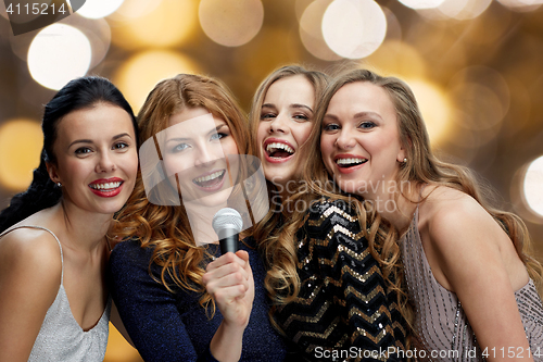 Image of happy young women with microphone singing karaoke
