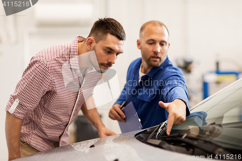 Image of auto mechanic with clipboard and man at car shop