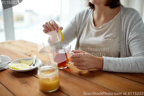 Image of close up of woman adding lemon to tea cup