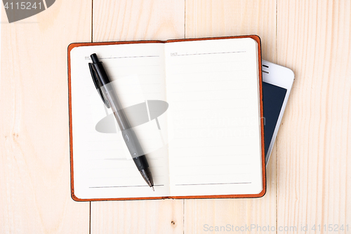 Image of Small notepad with pen and smartphone