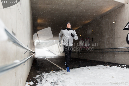 Image of man running along subway tunnel in winter