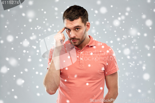 Image of man with finger at temple over snow background