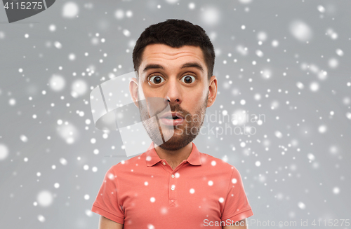 Image of surprised man in polo t-shirt over snow background