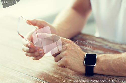 Image of close up of hands with smart phone and watch