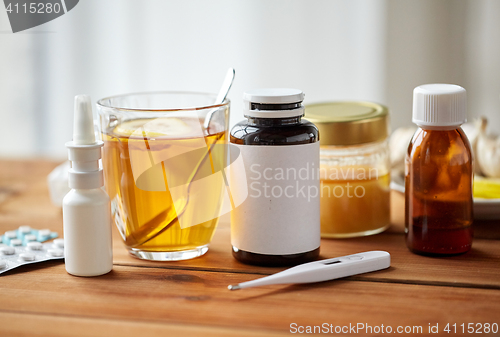 Image of drugs, thermometer, honey and cup of tea on wood