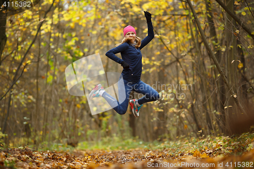 Image of Sportswoman running among autumn leaves