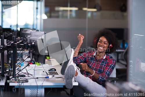 Image of woman at her workplace in startup business office listening musi