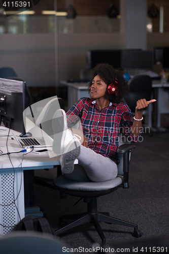 Image of woman at her workplace in startup business office listening musi