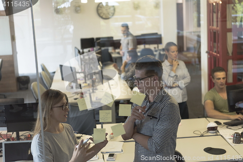 Image of young couple at modern office interior writing notes on stickers