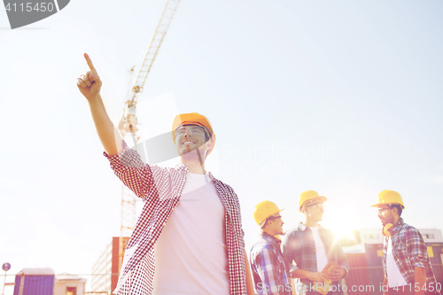 Image of group of smiling builders in hardhats outdoors