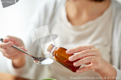 Image of woman pouring medicine from bottle to spoon