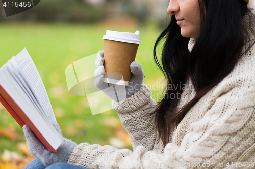 Image of woman with book drinking coffee in autumn park