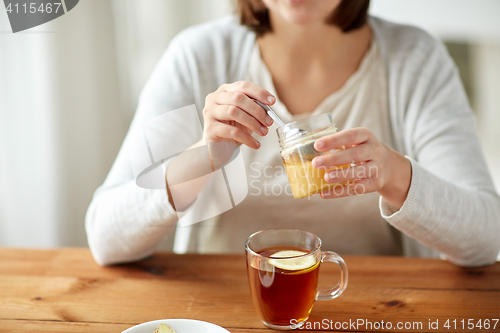 Image of close up of ill woman drinking tea with honey