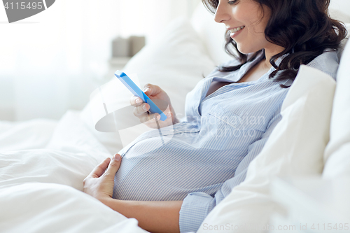 Image of close up of pregnant woman with smartphone in bed