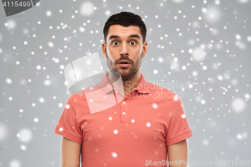 Image of surprised man in polo t-shirt over snow background