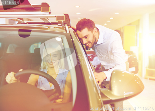 Image of happy couple buying car in auto show or salon