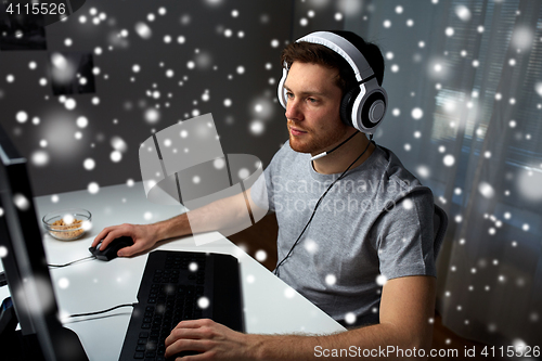 Image of man in headset playing computer video game at home