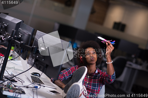 Image of young woman at her office workplace playing with plane toy