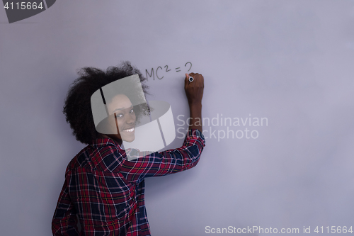 Image of black  woman writing on a white board  in a modern office