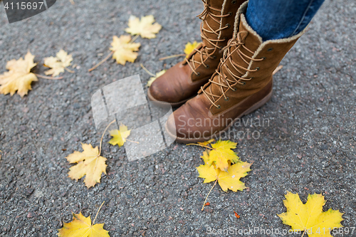 Image of female feet in boots and autumn leaves