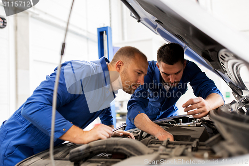 Image of mechanic men with wrench repairing car at workshop